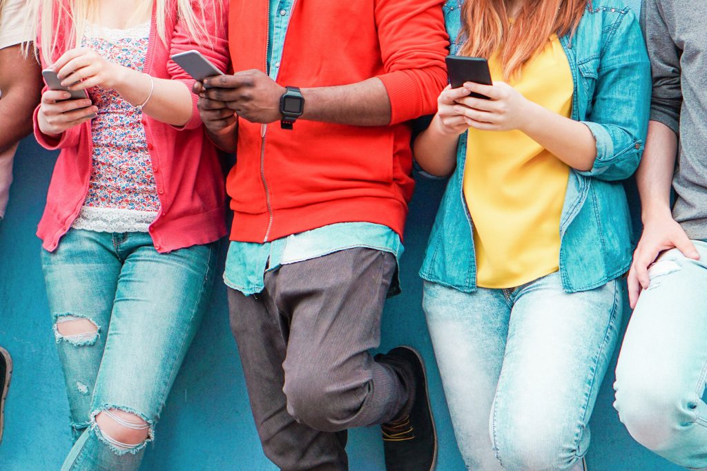 Group of young friends watching smart mobile phones